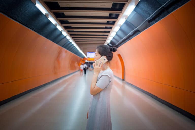 Female using a smart phone in a subway tunnel.