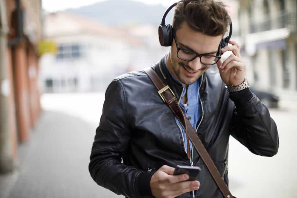 Smiling young man listening to music outdoors.