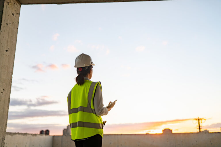 A young female engineer is using a digital tablet on a construction site.