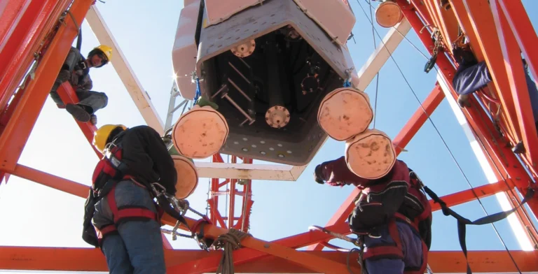 Technicians at a BAI broadcast tower lift a UHF antenna, Mt Goonaneman, QLD.