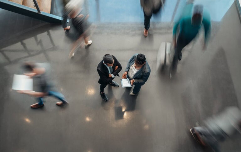 Two business people standing in the lobby of an office.