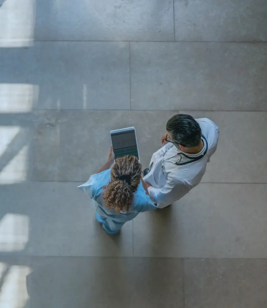 Aerial view of two doctors looking at a smart tablet.