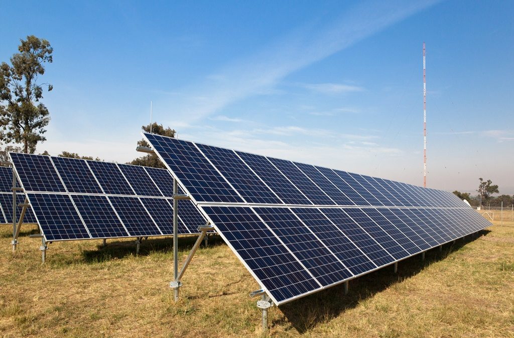 Solar panels in a field at Muswellbrook with a transmission tower in the background.