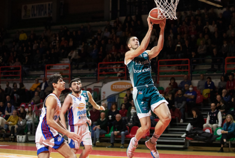 Basketball player jumping to sink a basket.