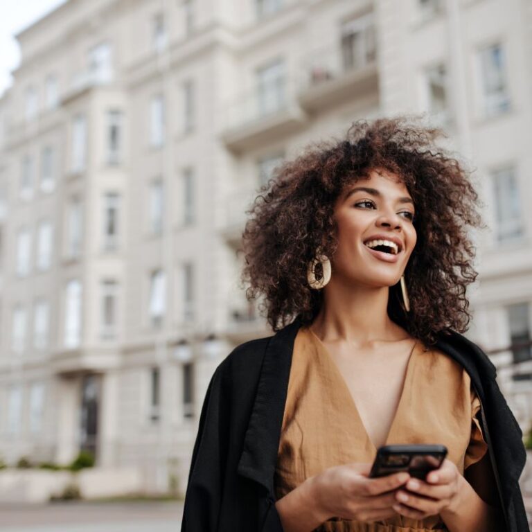 Young woman laughs while holding mobile phone.