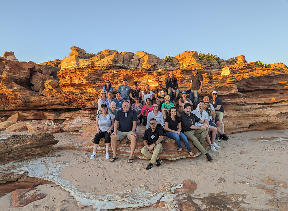 Jawun Executive Visit 2023 - group pose against rocky background at sunset.