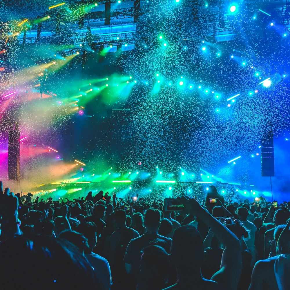 People at a concert use smartphones to capture images of lights and confetti.