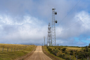 Modern communications tower juxtaposed with a timber fence line.