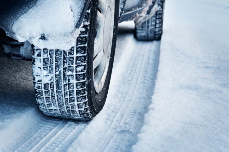 Close up of car tires driving through think snow.