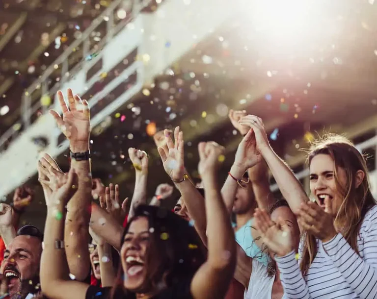 Young people at an event cheering with confetti raining down.