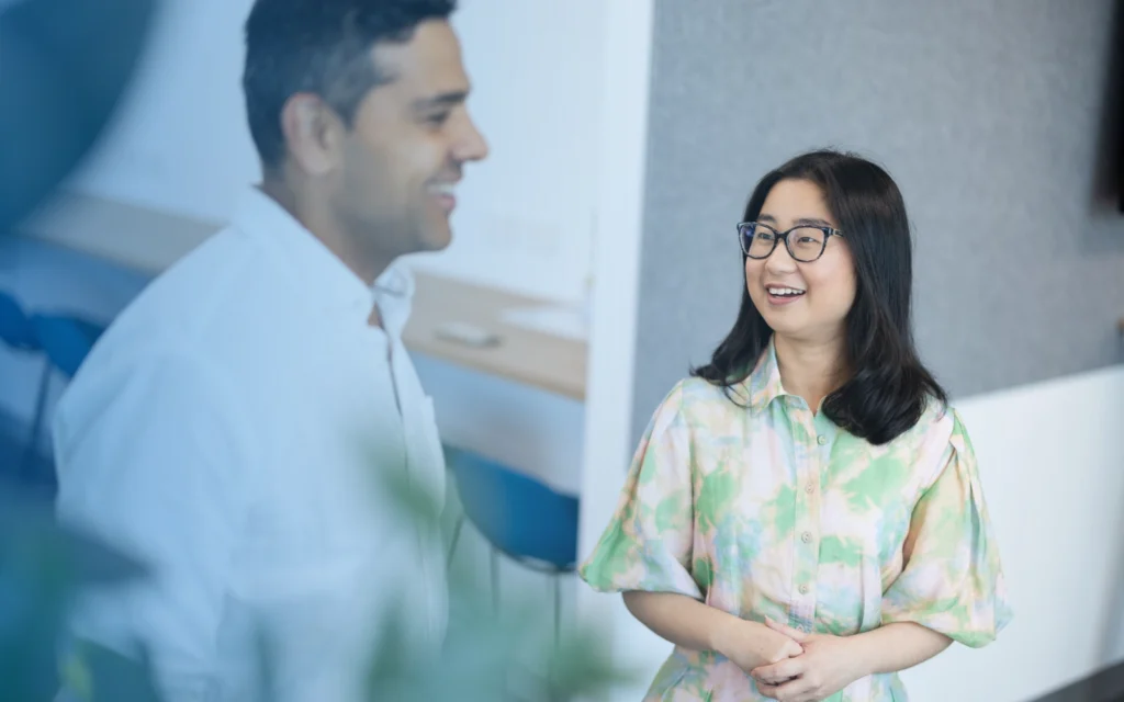 Image of a smiling woman looking at a male colleague.