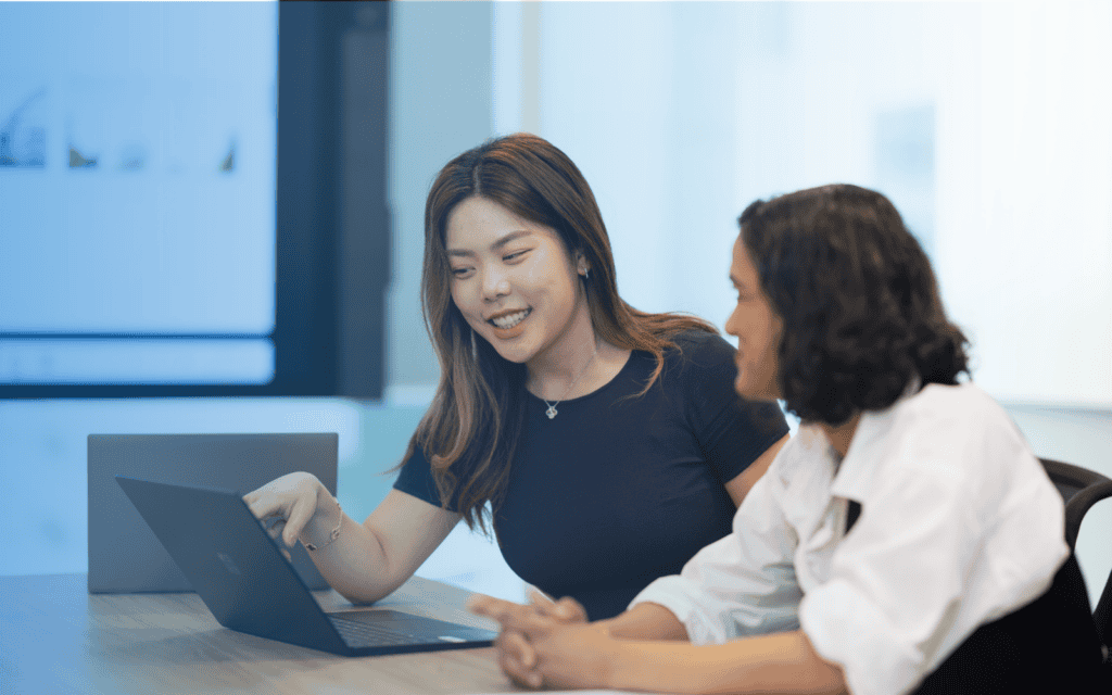 Two female colleagues look at a laptop.