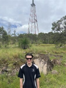 Ben, a BAI Broadcast Technician Apprentice pictured in front of a Broadcast Tower.